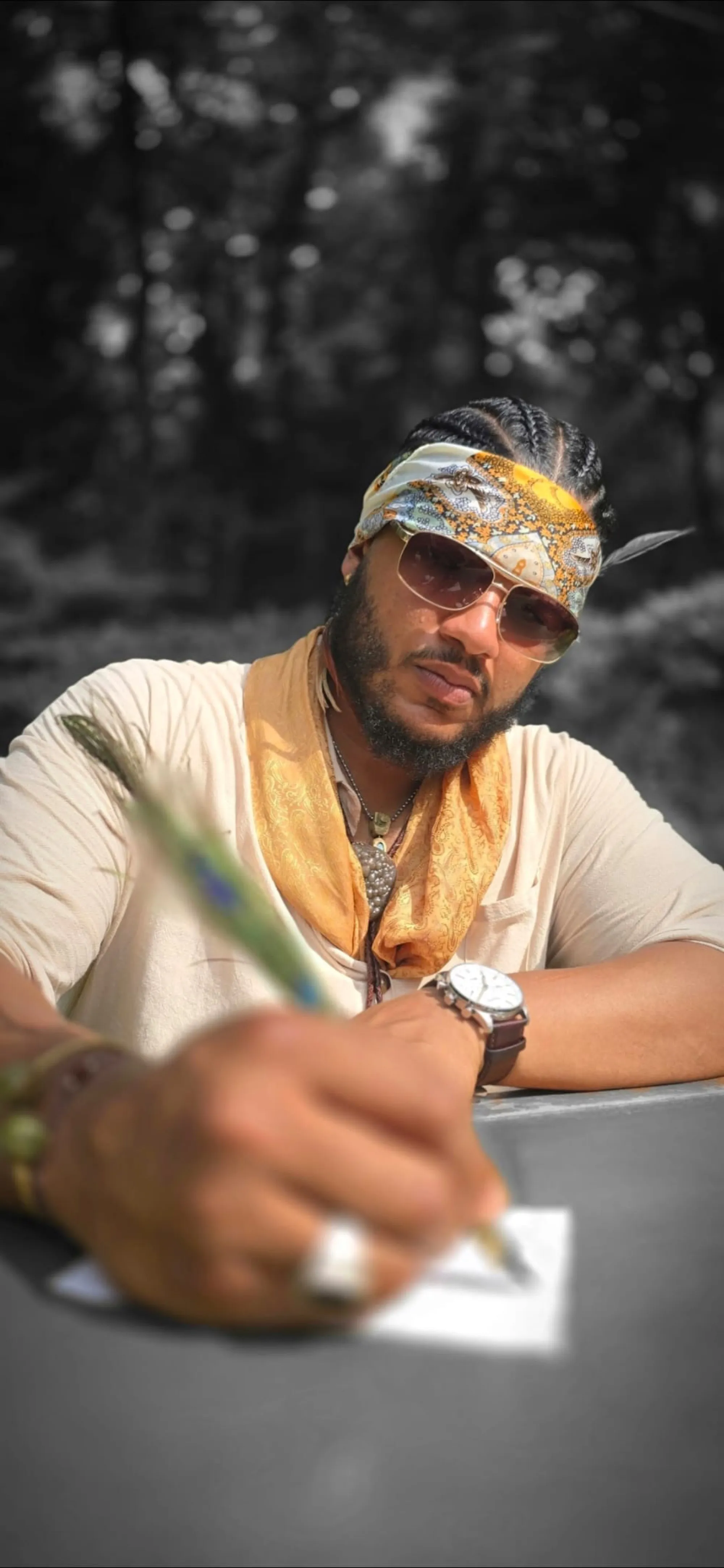 Benjamin Urbaez writing lyrics outdoors wearing patterned bandana and sunglasses, Dominican-American songwriter and spoken word poet