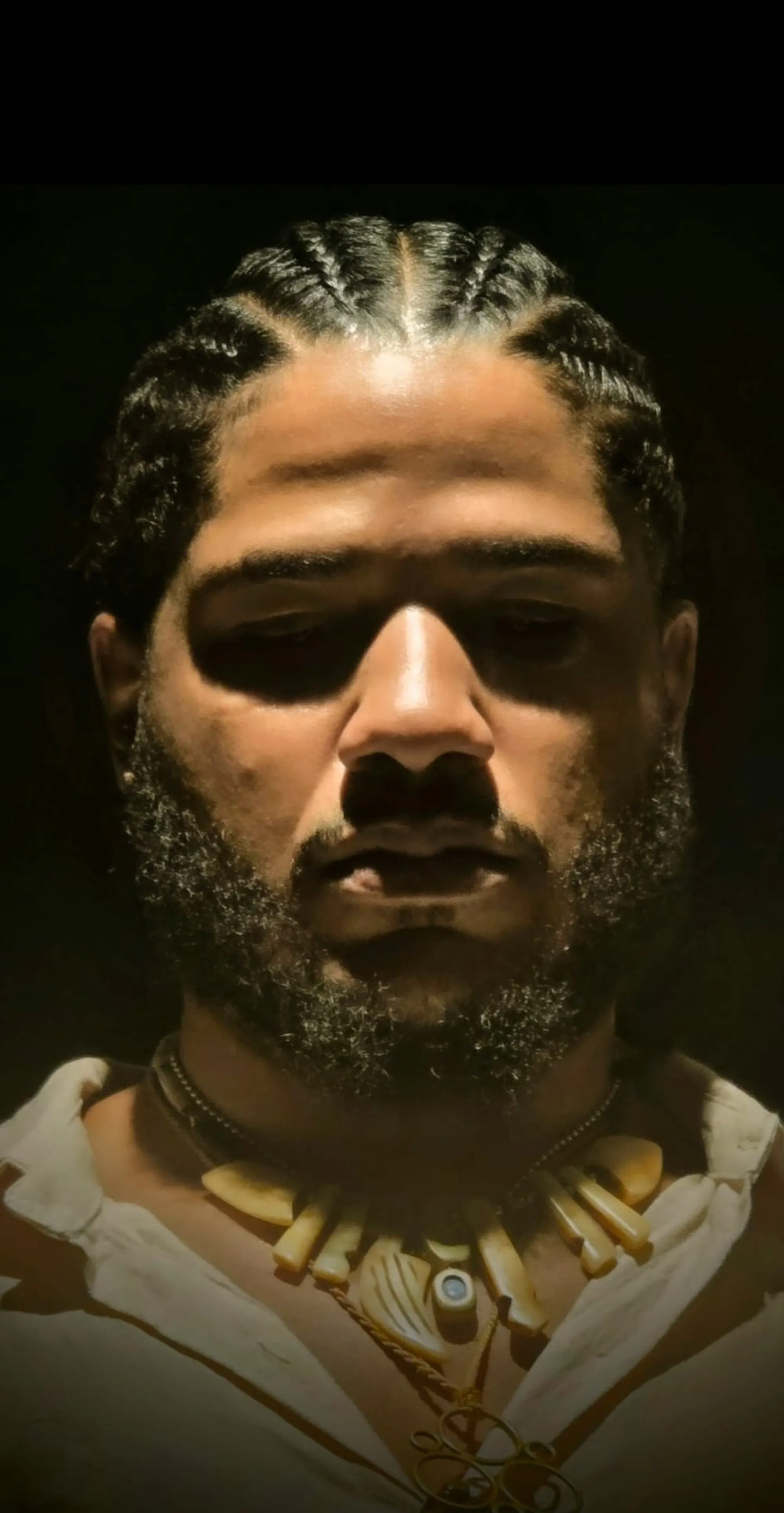 Benjamin Urbaez Dominican-American spiritual music artist in meditative close-up portrait wearing ancestral bone necklace