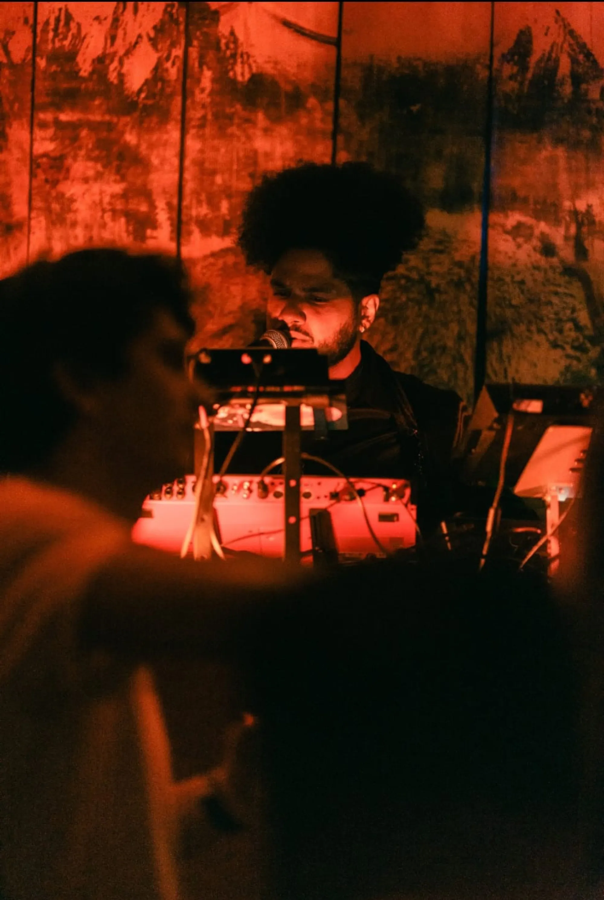 Global artist Benjamin Urbaez and DJ Dreeemy singing into microphone during live afrobeats performance with intimate red stage lighting